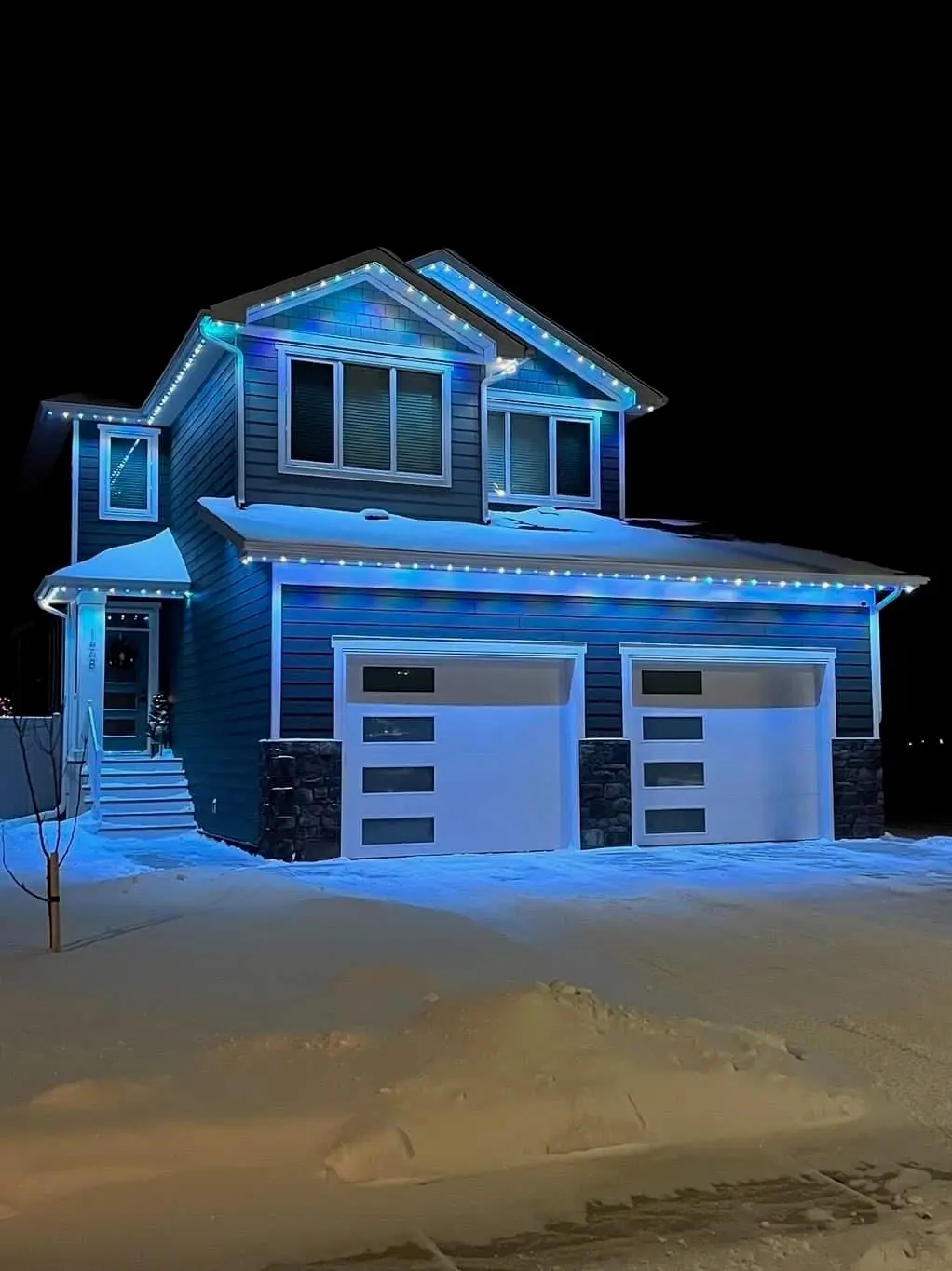 Home in winter lit with blue and teal permanent LED roofline lights