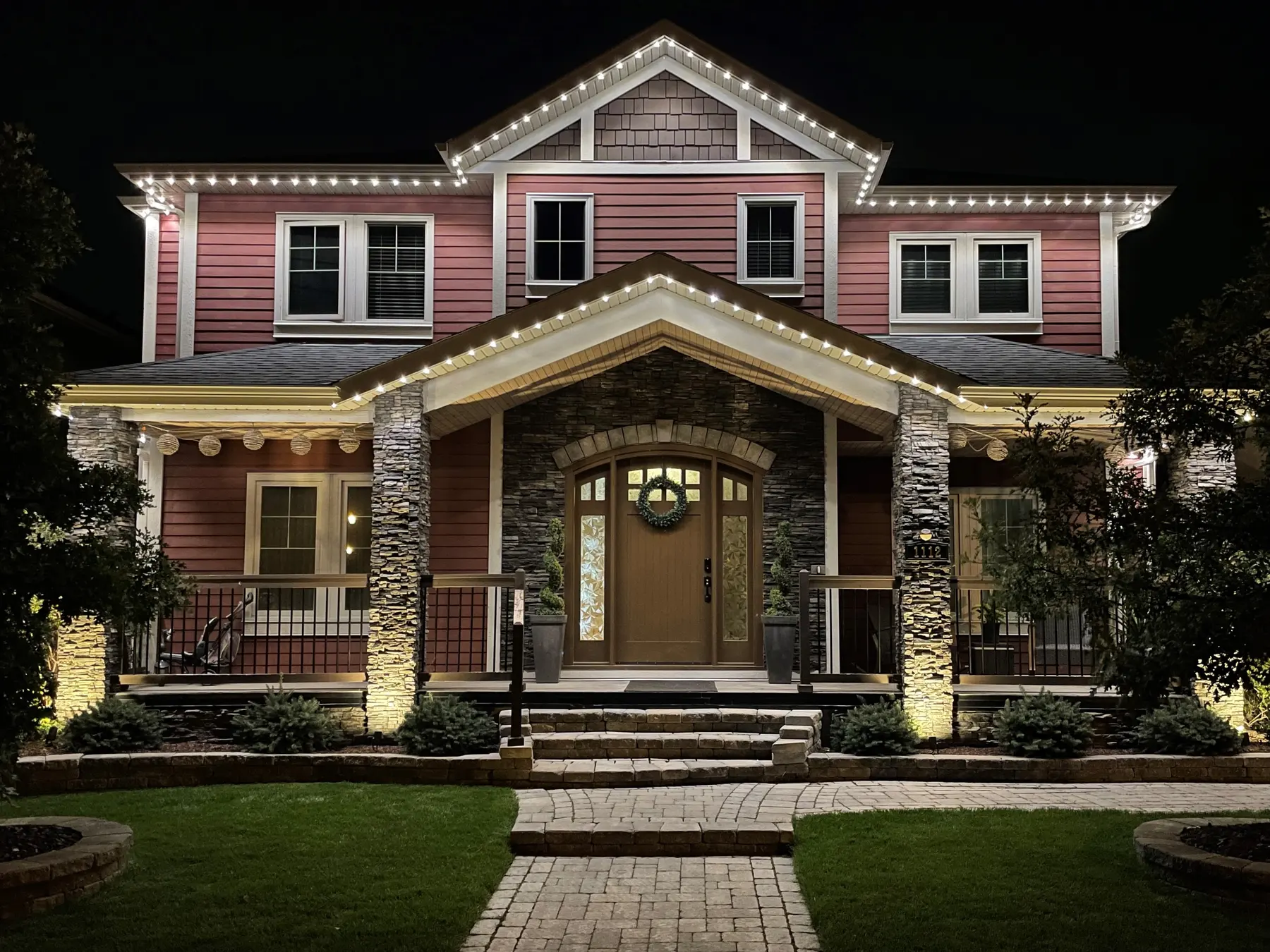 Two-story craftsman home with warm white permanent LED lights along every roofline and gable at night