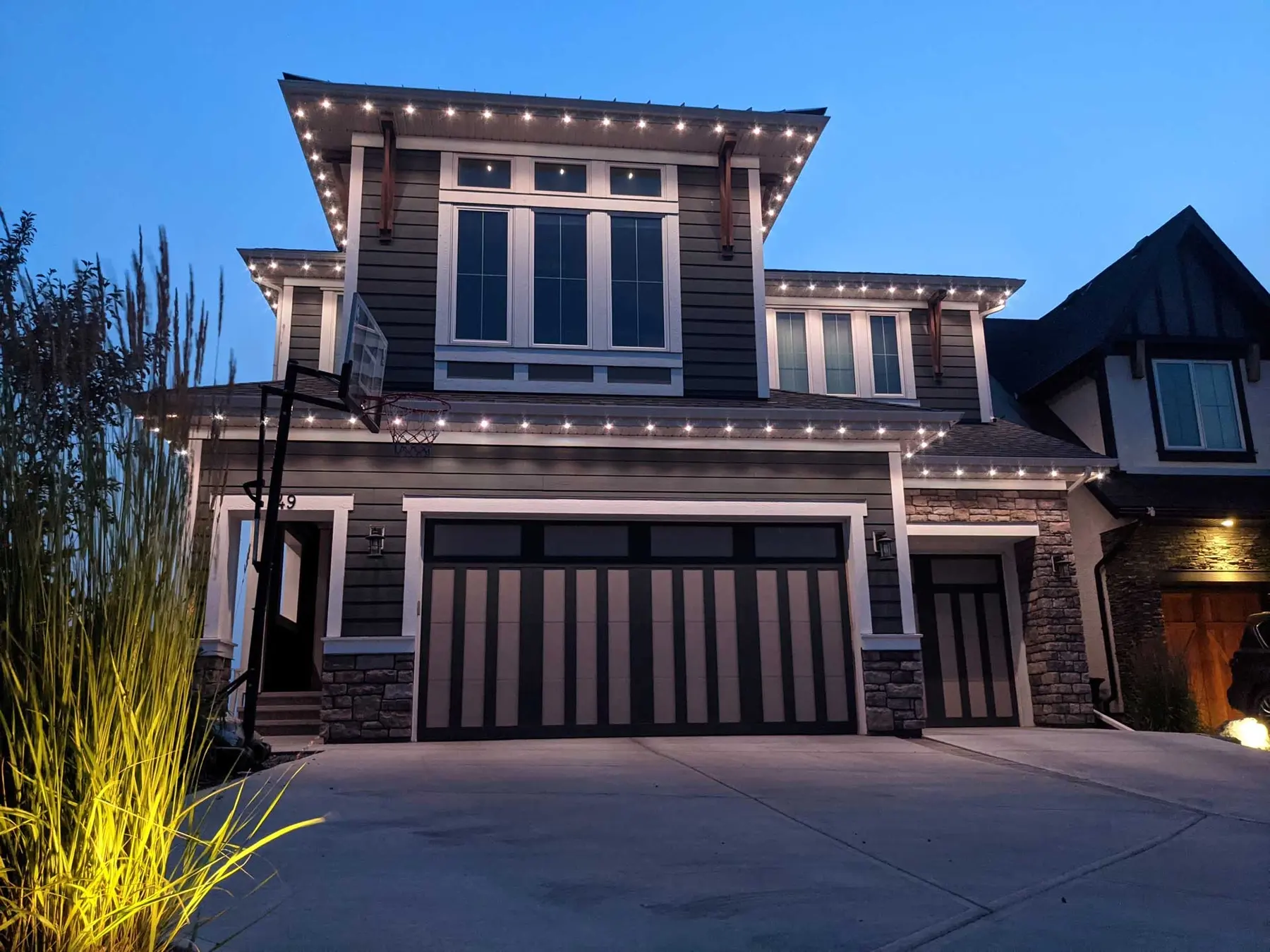 Permanent LED lights set into the soffit of a modern two-story home at dusk